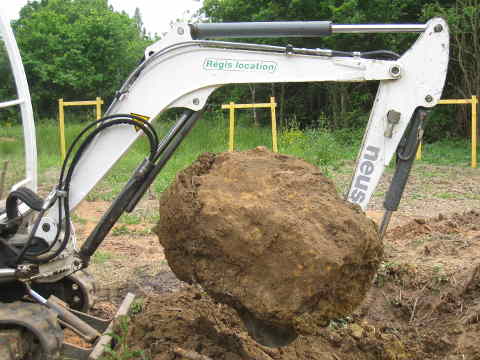 grosse pierre extraite du sol avec la mini-pelle